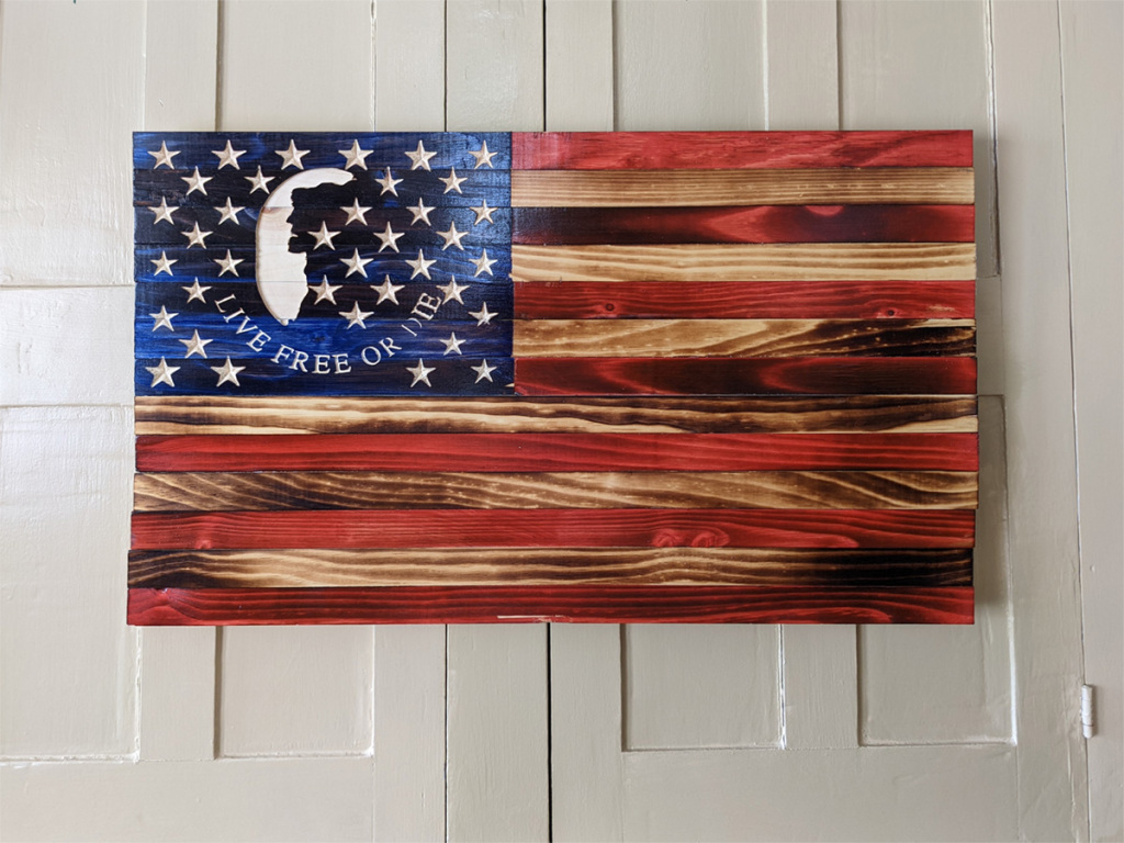 Wooden American Flag sign made from colored stained wood with the grid of stars and a live free or die emblem in the blue field